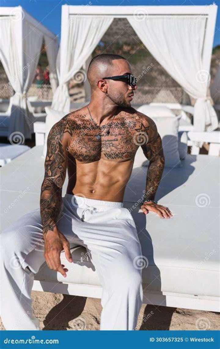a man with tattoos sitting on the ground